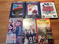 Photo showing six sports-themed VHS and DVD cases arranged on wooden surface.