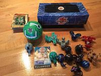 Full view of the lot showing Bakugan toys, large green Bakugan ball, cards, rulebook, and original box source