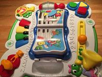 Top view of LeapFrog activity table showing piano keys, flip book, shape sorter buttons, and other interactive components