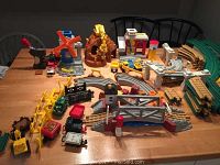 Full spread of Geotracks train set components including trains, tracks, quarry, and accessory buildings laid out on a wooden table.