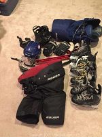 Photo showing the full lot of junior hockey equipment including helmets, gloves, pants, skates, stick holder, and protective gear all laid out on carpet.