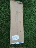 Full boxed whiteboard on grass showing intact packaging with tape and labels.