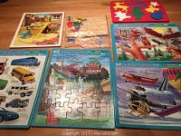 Full view of all seven puzzles spread on table, showing Bob the Builder, foam Christmas puzzle, Canada landmarks, vehicles, flying objects and birds puzzles.