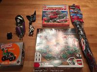 Overview of all items in the lot including the Transformer kite package, Hobbit Lego board game box, Meccano building set box, and various Transformers building components.