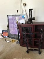 Cabinet with lattice doors, floor lamp, dual watt converter, Marilyn Monroe print, white small device on lamp base and wooden stand visible in room