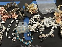 Mixed bracelets laying on flat surface showing various styles, colors and charms.