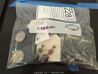 Plastic bag containing multiple pairs of pierced earrings with visible tags
