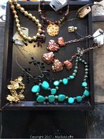 Tray with 7 necklaces laid flat showing variety of bead styles and pendants including gold-tone beads, leopard print pendant, textured metallic hearts, turquoise stones, black beads, gold chain, and black cord with buckle.