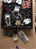 Tray with assorted new necklaces, earrings, and bracelets with tags in various colors and styles, lying flat for display.