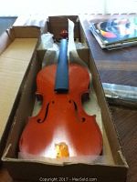Front view of unstrung violin in cardboard box
