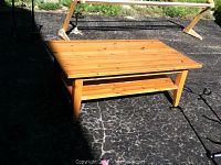 Full view of the pine coffee table outdoors showing the tabletop and lower shelf.