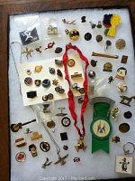 Flat lay of assorted pins showing various brands and icons including Hard Rock Cafe, Batman, Export A, and character pins spread out on a dark background with a red ribbon lanyard.