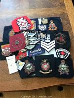 Full lot of assorted military and civilian cloth patches and badges laid out on a surface, including Canadian insignia and rank chevrons.