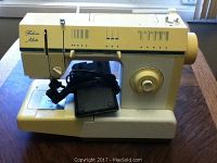 Side view of off-white Singer Fashion Mate sewing machine with electronic control panel, foot pedal placed on top of base.