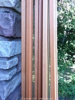 Three sets of beech color Ikea Billy bookcase glass panel doors shown leaning against a stone wall, close-up to show wood grain and glass.