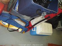 Photo showing a blue Coleman cooler and a blue folding chair bag on the floor.