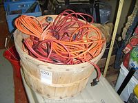 Basket filled with multiple orange extension cords of various lengths and one trouble light cord.