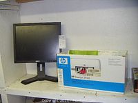 Dell 17 inch monitor next to HP Deskjet 3940 printer box on shelf