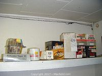 Shelf with packages including carburetor repair kit, oil filters, gasket material roll, and used spark plug wires.