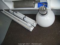 Two sets of fluorescent tube lights including double 48-inch, single 36-inch, and single 24-inch fluorescent tubes lying on the floor next to a large spherical ceiling lamp with white plastic globe.