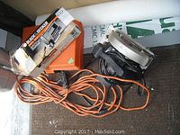 Photo showing Jobmate circular saw, Black & Decker jigsaw in original box, Black & Decker sander case, and an orange extension cord on floor.