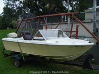 Starboard-side profile of 13-ft boat on trailer showing hull, windshield, seat and motor
