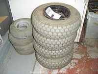 Two stacks of utility cart wheels; one stack of 4 larger wheels and one stack of 4 smaller wheels, tires appear worn and soft.