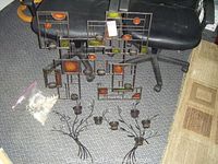 Metal wall art and decorative candle holders displayed on carpeted floor with office chair in background