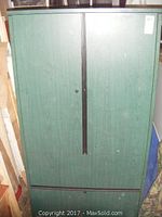 Full view of green office cabinet with two doors and file drawer at bottom