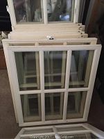 Two white painted six-light wood window sashes leaning upright against a wall