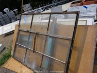 Main view of the steel-framed 9-light awning window leaning outdoors among building materials