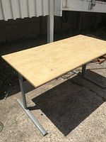 Front angled view of desk showing wood top, metal T-shaped legs, and overall size.