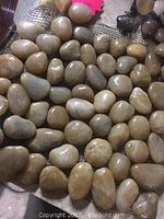 Close-up view of polished yellow river stones attached to mesh backing