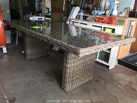 Wicker style patio dining table with tempered glass top viewed from side