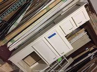 White painted reclaimed upper kitchen cabinets and microwave box shelf stacked upright showing front cabinet doors