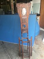 Full front view of the tall carved wooden wash stand with decorative panels and mirror, showing overall shape and construction.