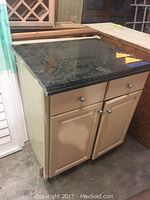 Front and side view of the reclaimed lower base cabinet with black granite countertop showing two doors and drawers with metal knobs.