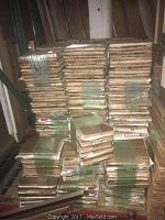 Stacks of reclaimed true oak parquet flooring squares bundled and stacked in a storage area with some duct tape and plastic wrap securing them.