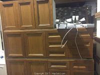 Lower kitchen cabinets with multiple drawers and wood paneled doors, medium brown wood finish