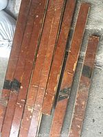 Nine reclaimed gym flooring wooden planks from Milby High School, with varnished finish and visible wear and markings.