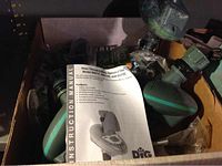 Box containing green and gray plastic garden sprinklers and various sprinkler accessories plus instruction manual.