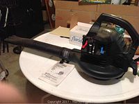 Side view of a Craftsman blower vacuum with long nozzle and operator manual on a white table.