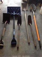Photo showing 6 shovels including a snow shovel and spades arranged on floor