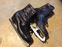 Pair of black leather ice skates showing overall condition and lacing