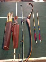 Overview showing two bows, two leather quivers, and multiple arrows arranged on a table