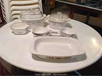 Photo showing assorted white Corningware cookware with blue floral pattern and a rectangular baking dish with multicolored floral design on the side.