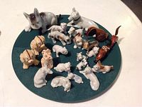 Overhead view of 23 ceramic small dog figurines arranged on a circular green surface.