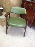 Front view of one mid-century office chair showing olive vinyl seat and back padding with wooden armrests and legs.