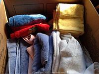 Box of assorted towels showing bath towels, hand towels, and bath mat towels in multiple colors.
