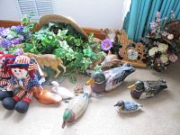 Photo showing cloth doll, duck decoys, deer figurine, and floral arrangements on carpet